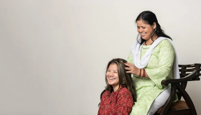 a woman sitting next to a woman who is brushing her hair